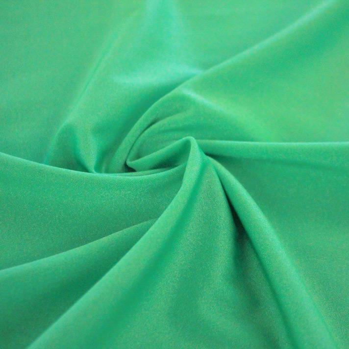 A swirled sample of Charisma shiny nylon spandex in the color green.