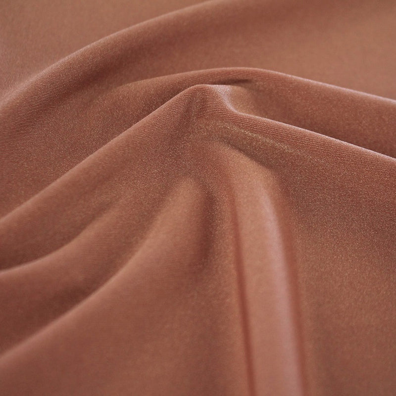 A swirled sample of Charisma shiny nylon spandex in the color topaz.