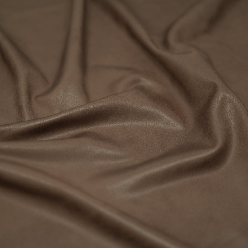 A crumpled piece of Cowboy Faux Leather Foil Printed Spandex in the color Brown
