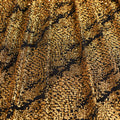 A draped sample of dancing snale glitter stretch mesh in the color black-gold.
