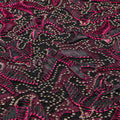 A flat sample of in flight embroidered mesh in the color black-magenta-gold.