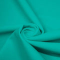 A swirled piece of matte nylon spandex fabric in the color aqua tides.