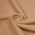 A swirled piece of matte nylon spandex fabric in the color honey beige.