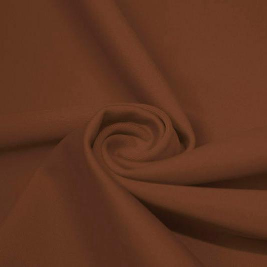 A swirled piece of matte nylon spandex fabric in the color sweet syrup.