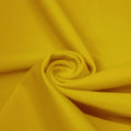 A swirled piece of microfiber nylon spandex in the color halei yellow.