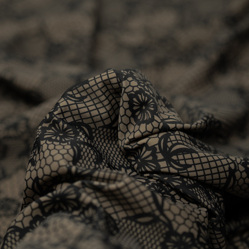 A crumpled piece of Black Illusion Lace Pattern on Brown Printed Spandex