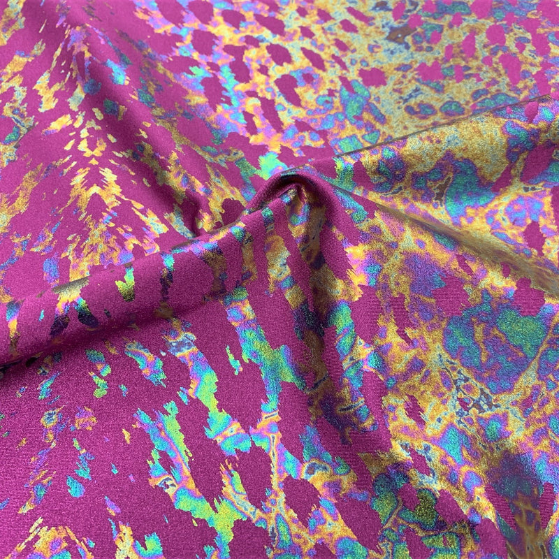 A swirled sample of naga foil printed spandex in the color mulberry/iridescent.