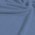A swirled sample of popcorn polyester spandex jacquard in the color easy breezy blue.
