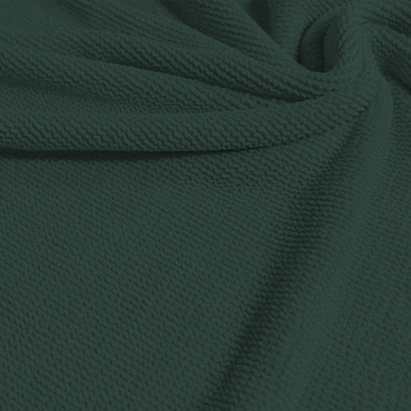 A swirled sample of popcorn polyester spandex jacquard in the color pale cacti green.