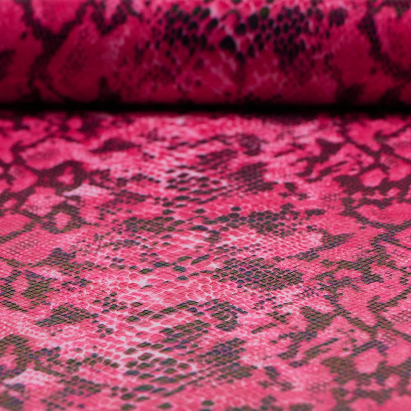 A folded sample of rattlesnake foil printed spandex in the color pink.