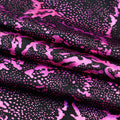 A folded sample of Metallic Reef Hologram Spandex Fabric in the color Black/Fuchsia