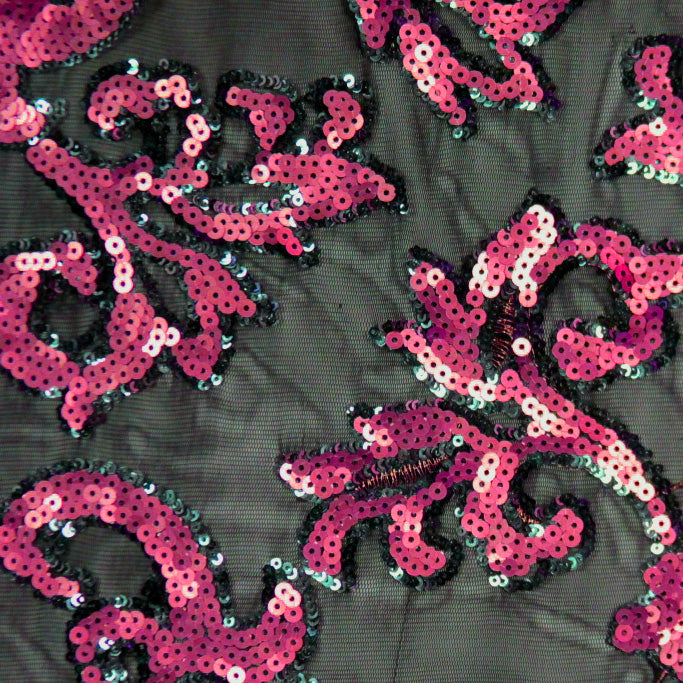 A flat sample of applique stretch mesh with fuchsia sequin on black mesh.