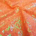 A swirled sample of arriba sequin spandex in the color hot-coral.