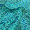 A swirled sample of arriba sequin spandex in the color turquoise.