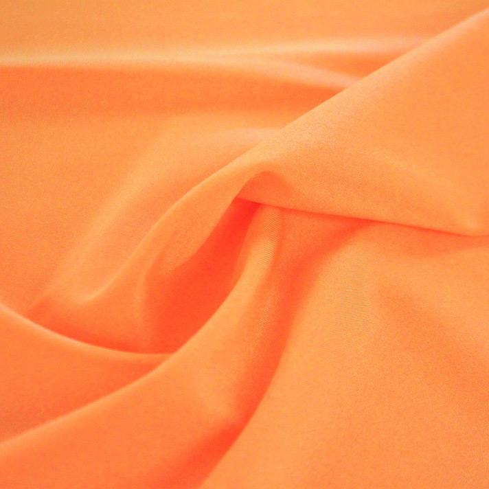 A swirled sample of Charisma shiny nylon spandex in the color tangerine.