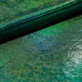 A folded sample of cobra foil printed stretch velvet in the color green.