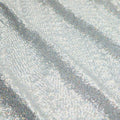 A panel of Cosmic GLOW spandex sequin in silver available at Blue Moon Fabrics.
