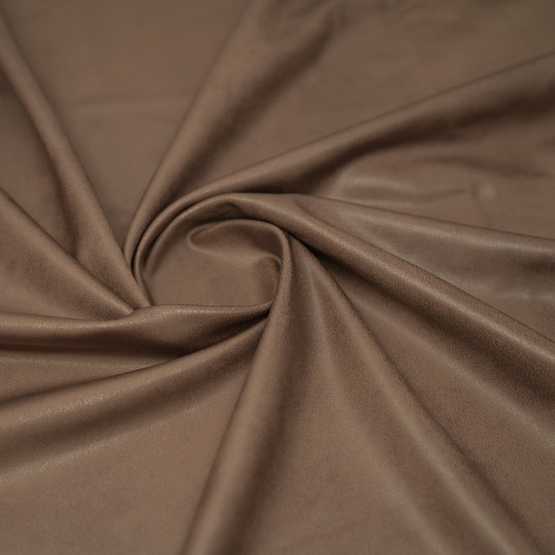 A swirled piece of Cowboy Faux Leather Foil Printed Spandex in the color Brown