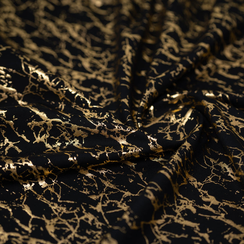 Swirled piece of Cracked Foil Printed Microflex in the color Black/Gold