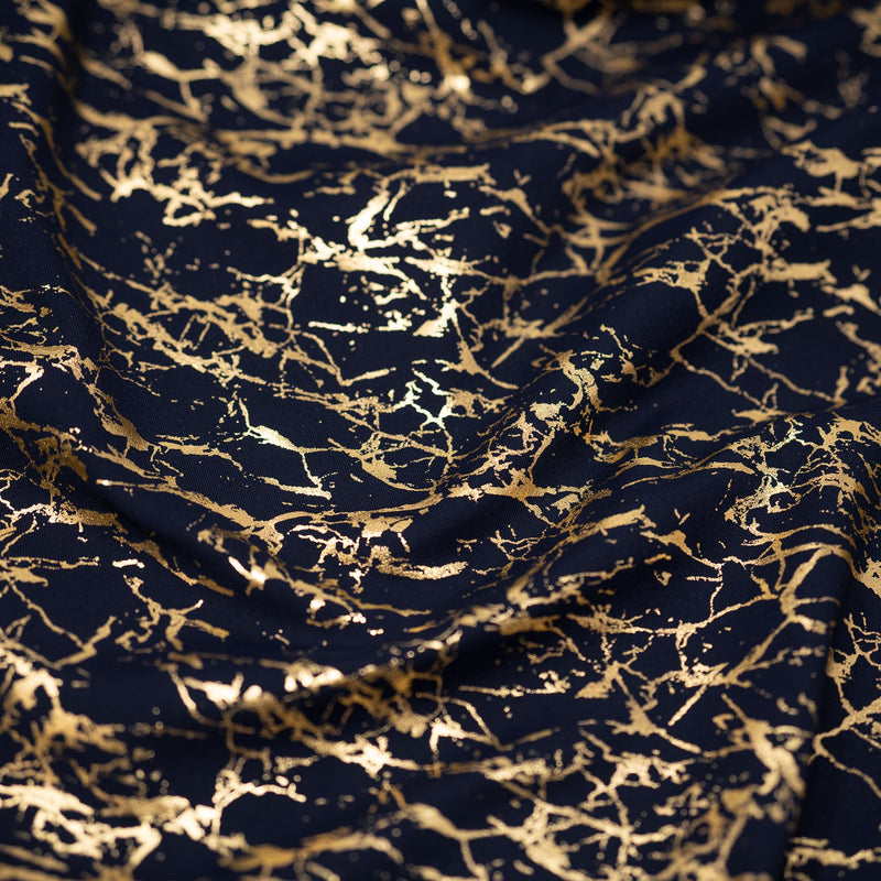 A crumpled piece of Cracked Foil Printed Microflex in the color Navy/Gold