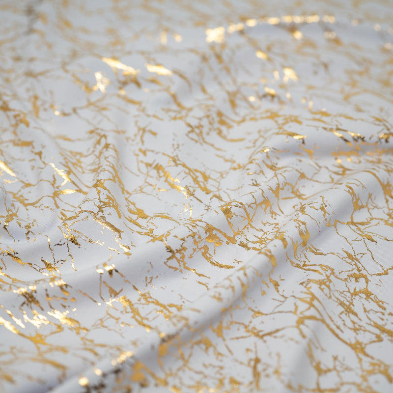 A crumpled piece of Cracked Foil Printed Microflex in the color White/Gold