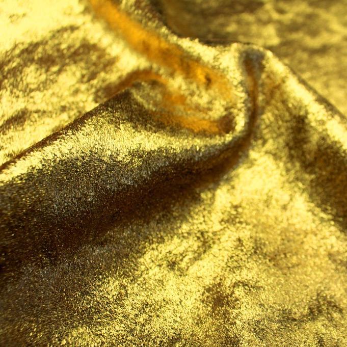 A swirled sample of d-isis foiled stretch velvet in the color gold.