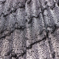 A draped sample of dancing snale glitter stretch mesh in the color black-silver.