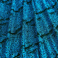 A draped sample of dancing snale glitter stretch mesh in the color black-turquoise.