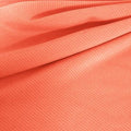 A draped sample of double ribbed spandex in the color coral.