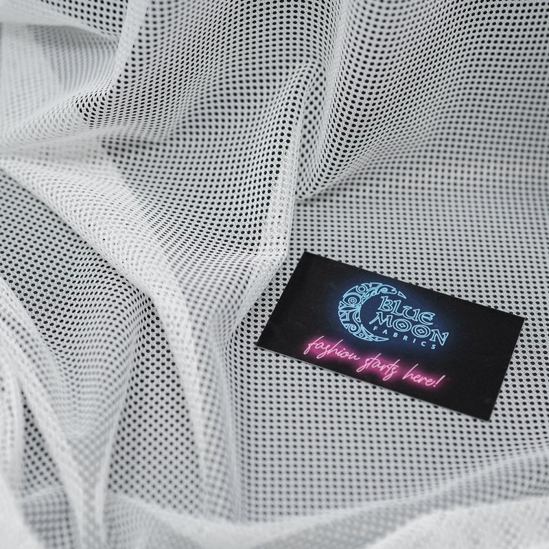 A crumpled piece of Polyester Mesh Tricot Boardshort and Swim Trunk Lining in the color White with a Blue Moon Fabrics standard size business card laid on top of the print for pattern sizing.