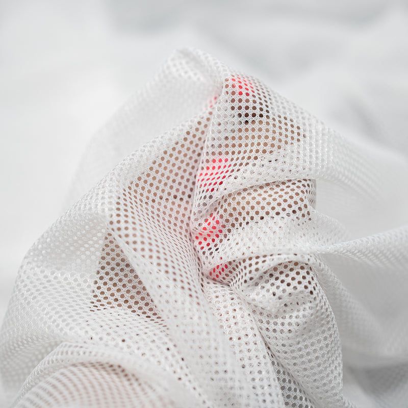 Hands playing with a sample of Polyester Mesh Tricot Boardshort and Swim Trunk Lining in the color White