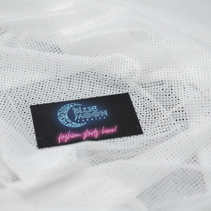 A sample of Polyester Mesh Tricot Boardshort and Swim Trunk Lining in the color white with a Blue Moon Fabrics standard size business card laid on top of the print for pattern sizing.