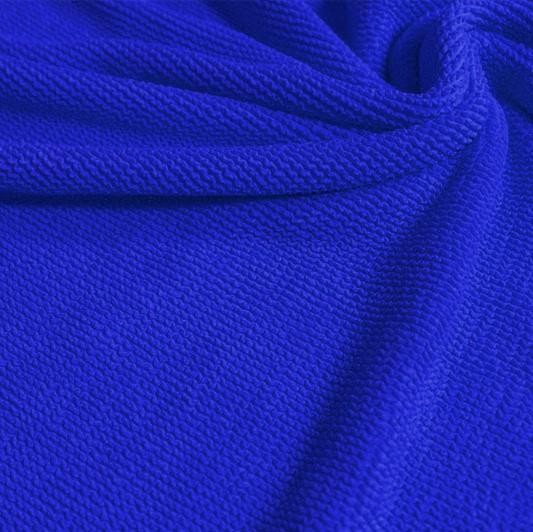 A swirled piece of crinkle polyester spandex jacquard fabric in the color deep royal.