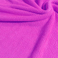 A swirled piece of crinkle polyester spandex jacquard fabric in the color mixed pink.