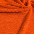 A swirled piece of crinkle polyester spandex jacquard fabric in the color rust.