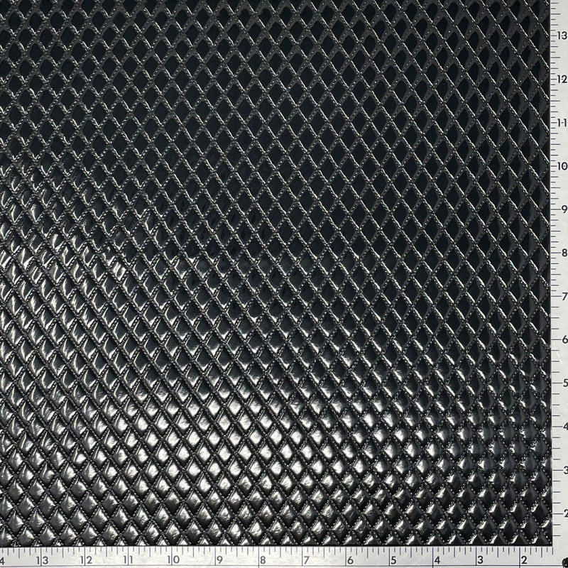 A sample of quilted hipster polyurethane coated spandex in the color black with a ruler for scale. 