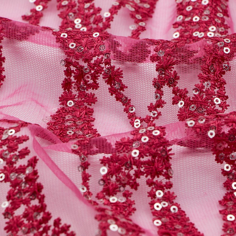 A flat sample of forget me not embroidered mesh in the color fuchsia.