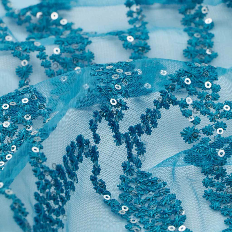 A flat sample of forget me not embroidered mesh in the color turquoise.