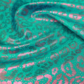 A swirled sample of fun leo foil printed spandex in the color green-fuchsia.