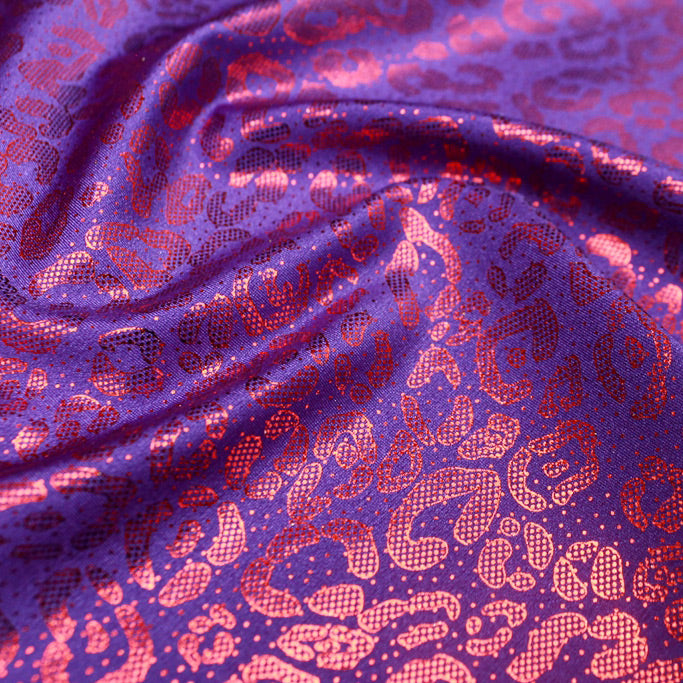 A swirled sample of fun leo foil printed spandex in the color purple-red.