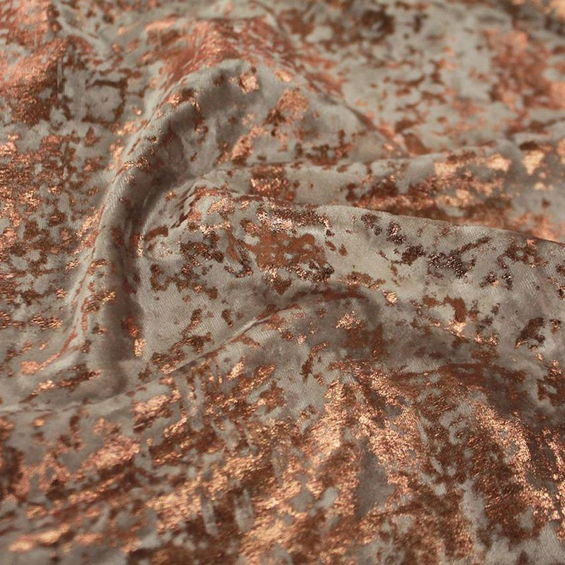 A swirled sample of gilded stretch velvet in the color taupe-rose gold.