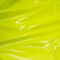 A swirled piece of polyurethane coated polyester spandex in the color Fluorescent-Yellow
