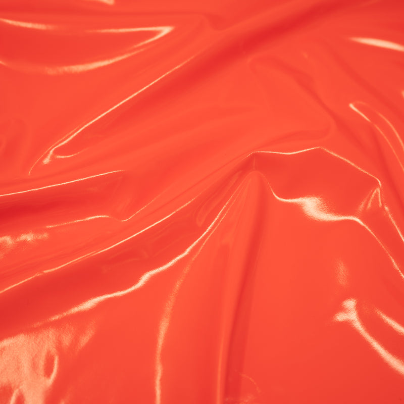 A swirled piece of polyurethane coated polyester spandex in the color Neon-Orange
