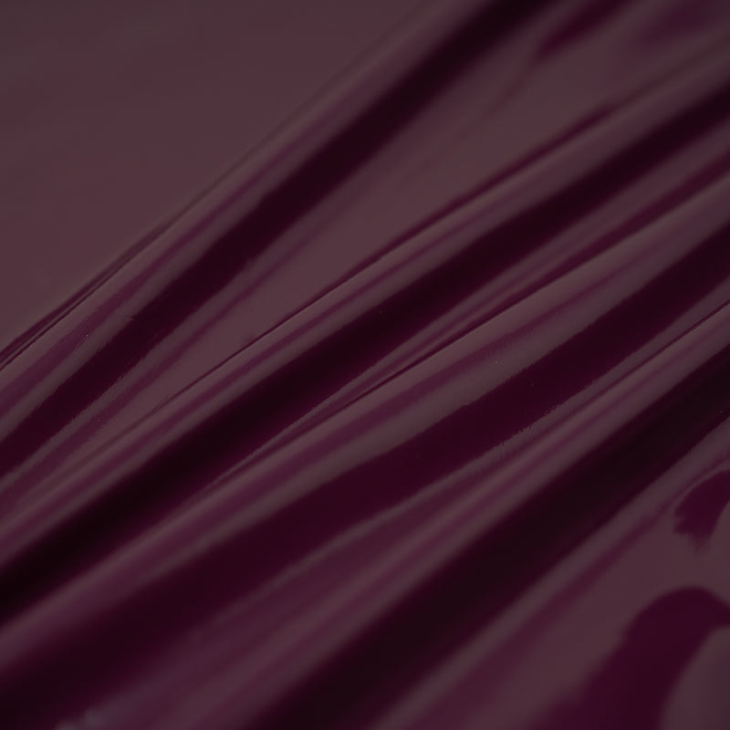 A swirled piece of polyurethane coated polyester spandex in the color Burgundy