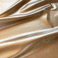 A swirled piece of polyurethane coated polyester spandex in the color gold.