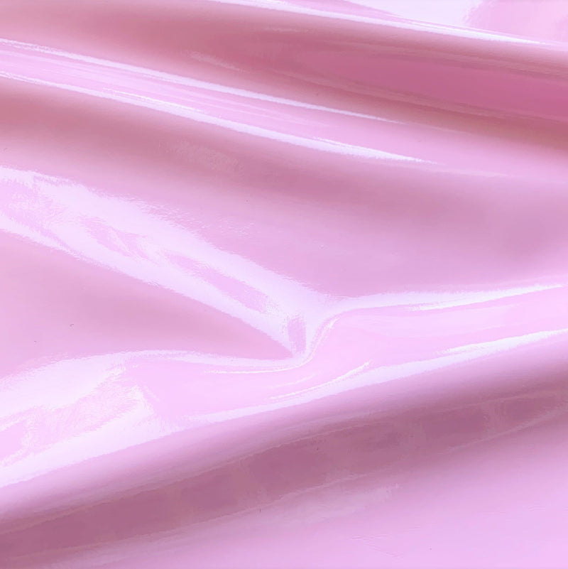 A swirled piece of polyurethane coated polyester spandex in the color light pink.