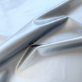 A swirled piece of polyurethane coated polyester spandex in the color silver.