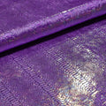 A folded sample of illusion anaconda foil printed stretch velvet in the color purple.