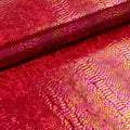 A folded sample of illusion anaconda foil printed stretch velvet in the color red.
