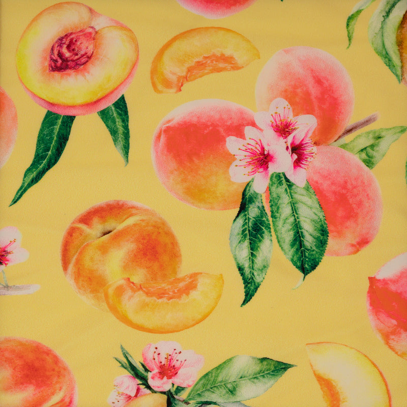 Flat sample shot of It's All Peachy Printed Spandex Fabric. The print is of whole peach clusters with pink peach blossoms and green leaves, whole individual peaches with peach slices and peach halves on a yellow toned background.  